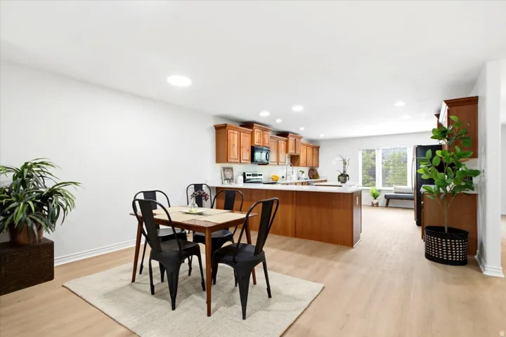 Spacious open-concept area featuring light wood-finish flooring, recessed lighting, and white walls
