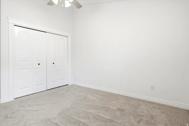 Bedroom featuring plush carpet flooring, white walls, and a ceiling fan