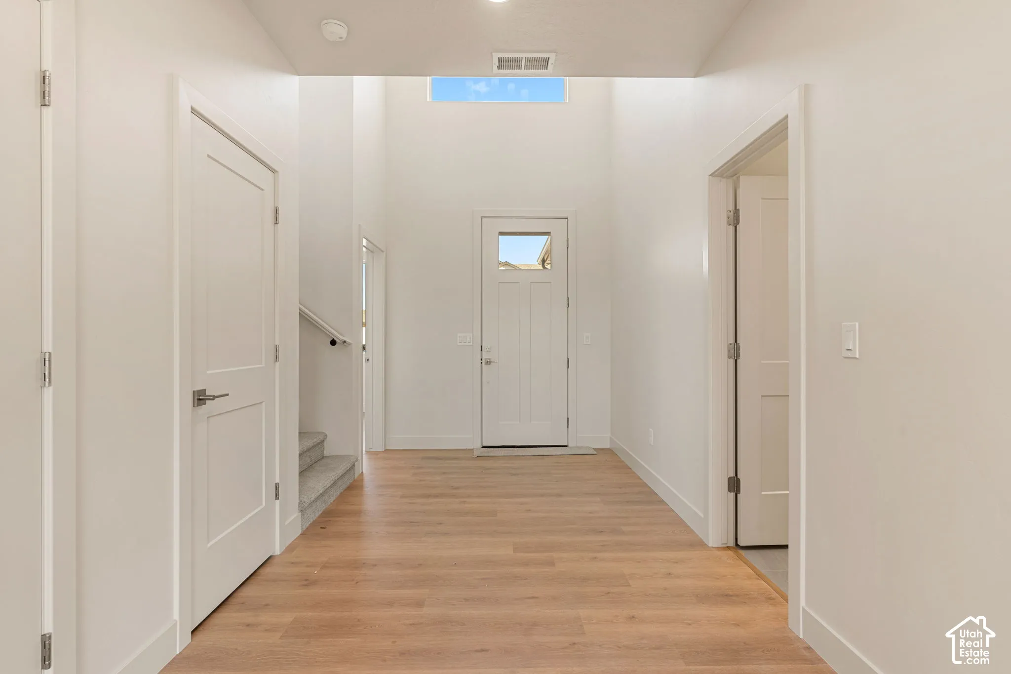Entryway featuring high ceilings, wood-finish flooring, a transom window, and paneled interior doors