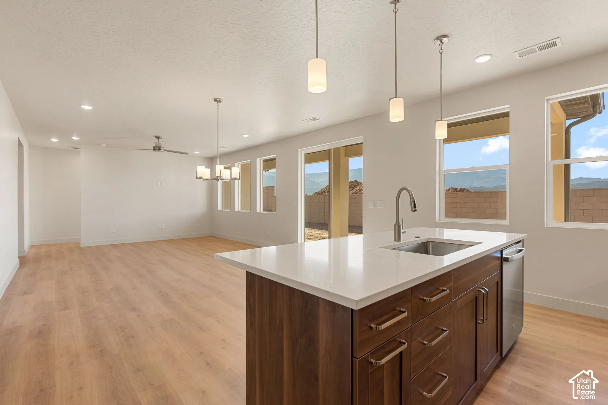 Kitchen island featuring a solid-surface countertop, under-mount stainless steel sink, and dark wood-finish cabinetry
