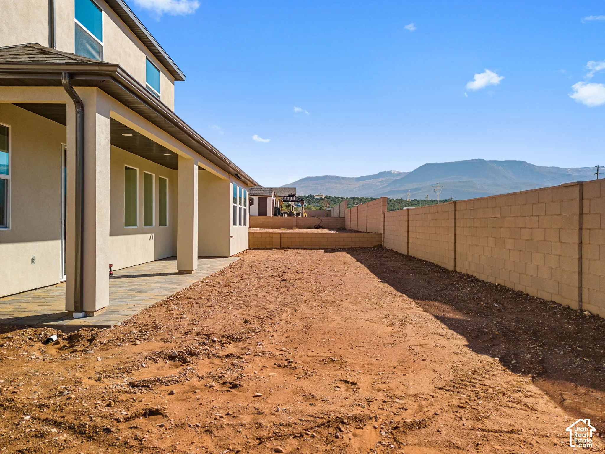Covered patio with stone-finish pavers, masonry block privacy wall, and mountain backdrop