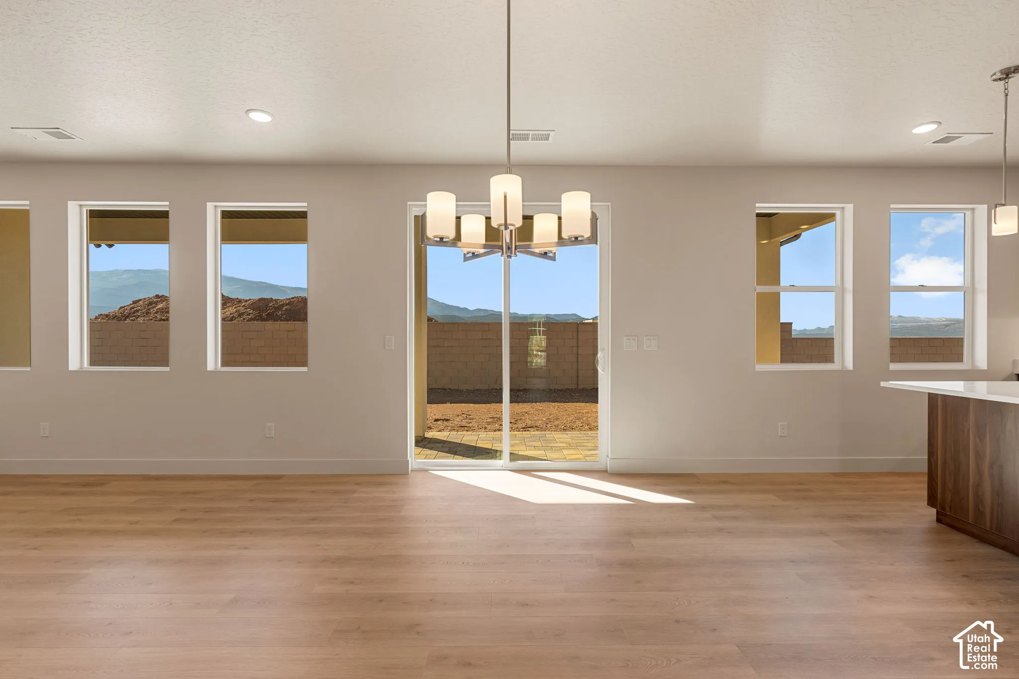 Open-concept interior featuring wood-finish flooring, multi-light chandelier, recessed lighting, expansive windows, and a sliding glass door