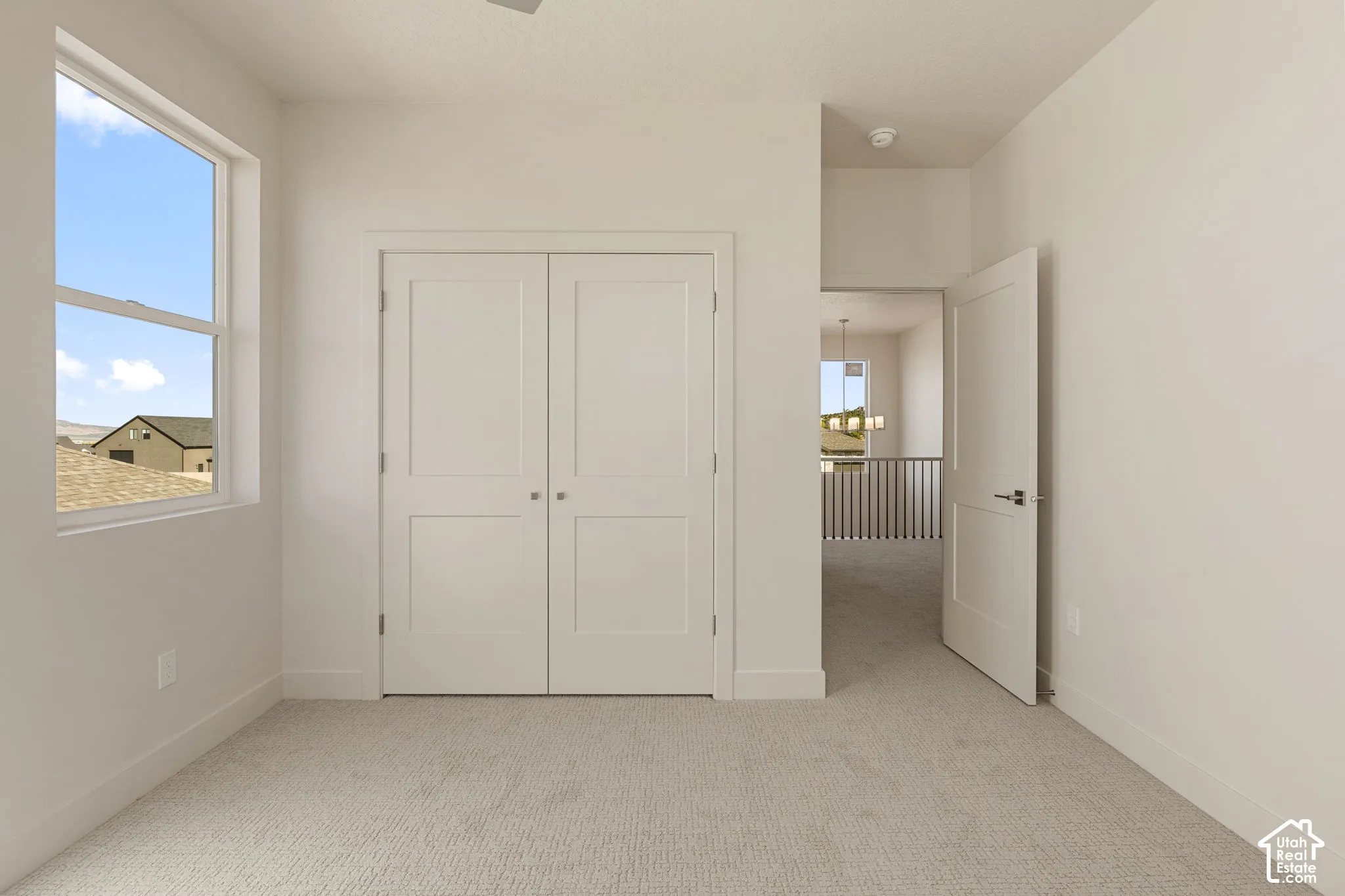Room featuring neutral-toned carpeting, dual-panel closet doors, and a single-hung window