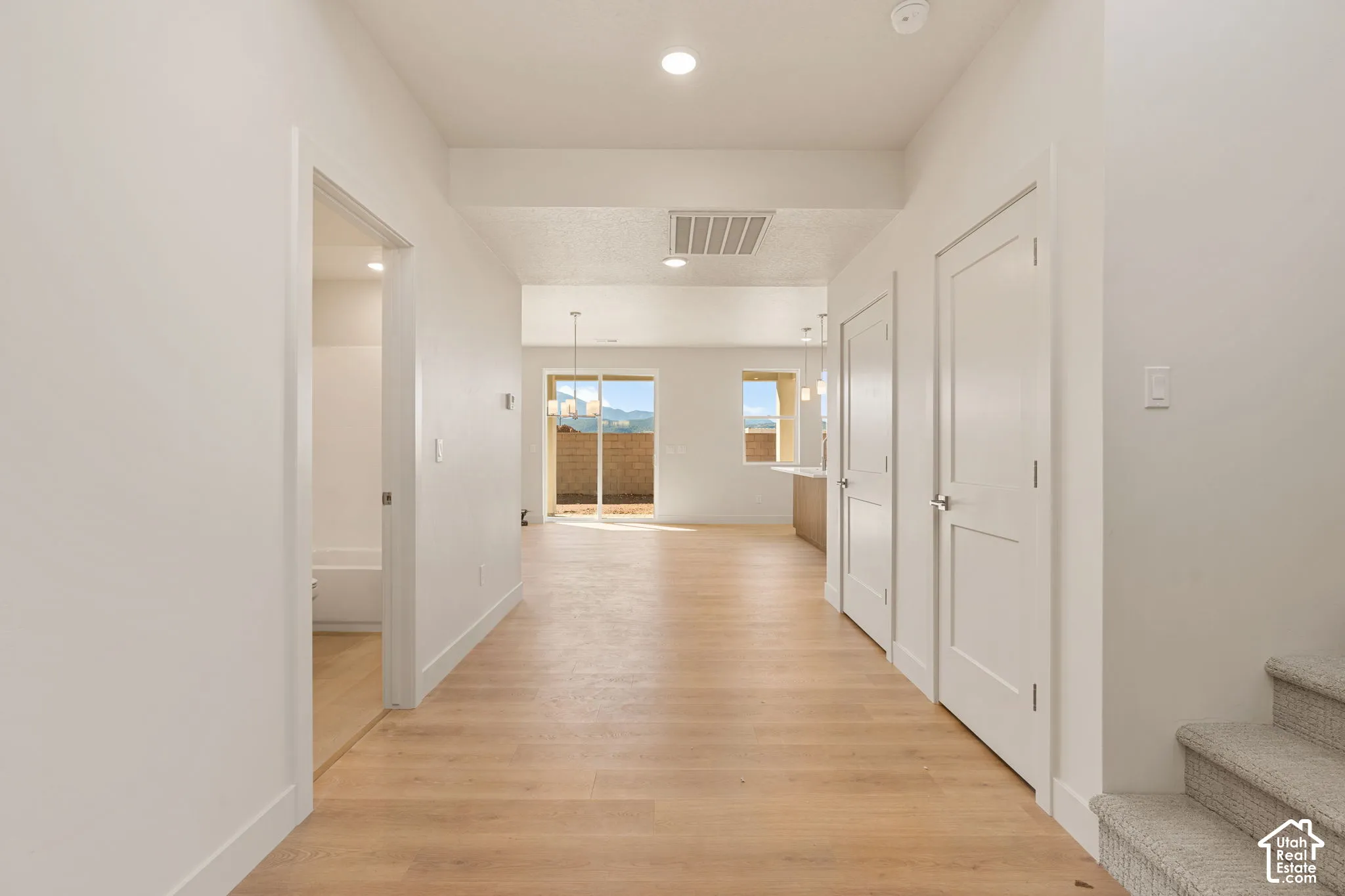 Interior hallway featuring wood-finish flooring, recessed lighting, multi-panel doors, and neutral paint tones