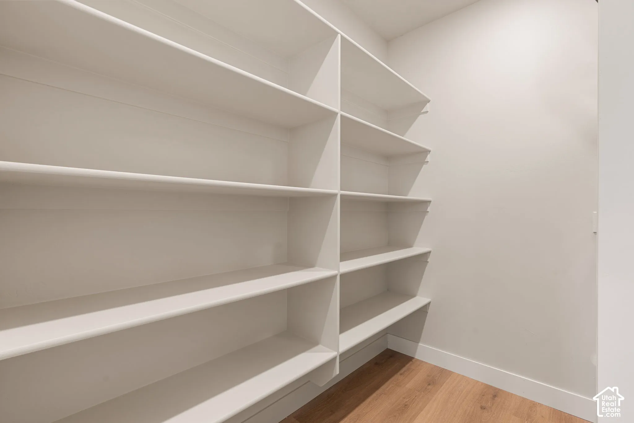 Custom built-in shelving featuring white laminate finish and wood-finish flooring