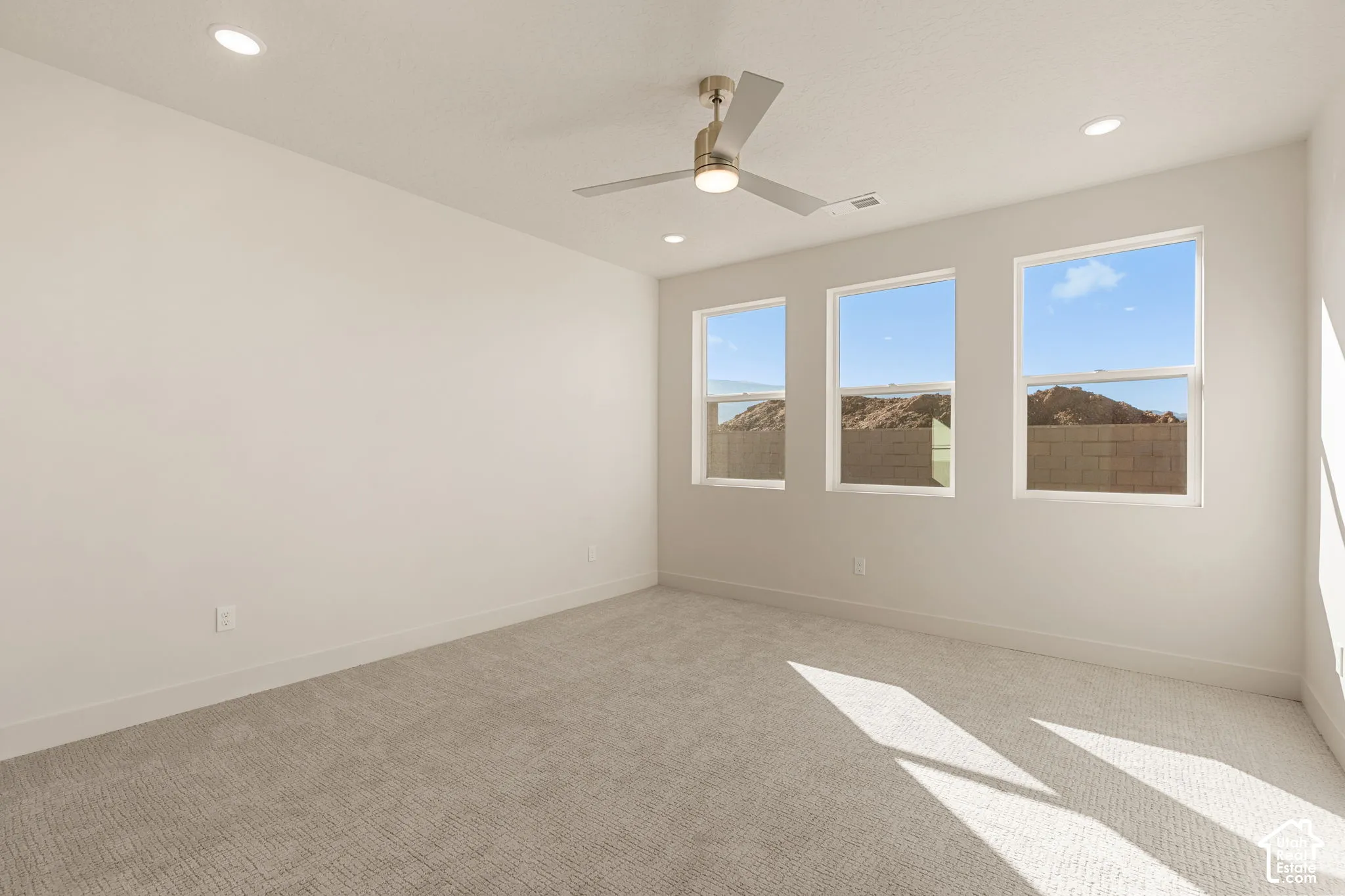 Neutral-toned interior space featuring wall-to-wall carpeting, recessed ceiling lighting, and a brushed nickel ceiling fan with integrated lighting