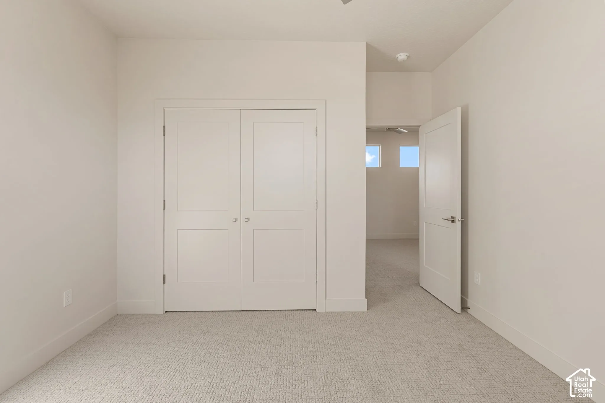Neutral-toned interior space featuring light carpeting, two-panel interior doors, and high-set transom windows