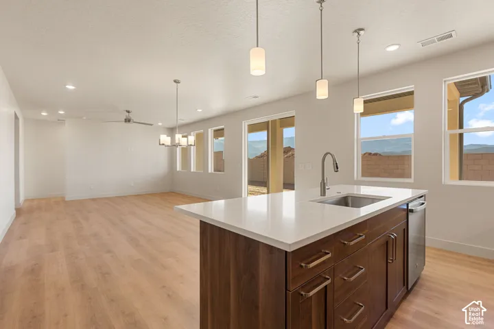 Kitchen island featuring a solid-surface countertop, under-mount stainless steel sink, and dark wood-finish cabinetry