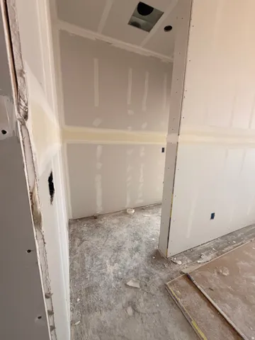 Unfinished interior space featuring drywall installation, exposed utility rough-ins, and concrete subflooring