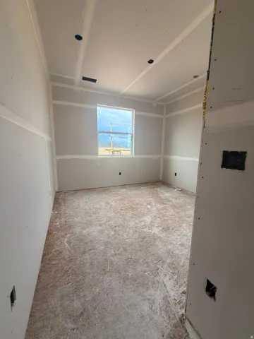 Drywall interior featuring a window, ceiling can lights, and exposed subfloor