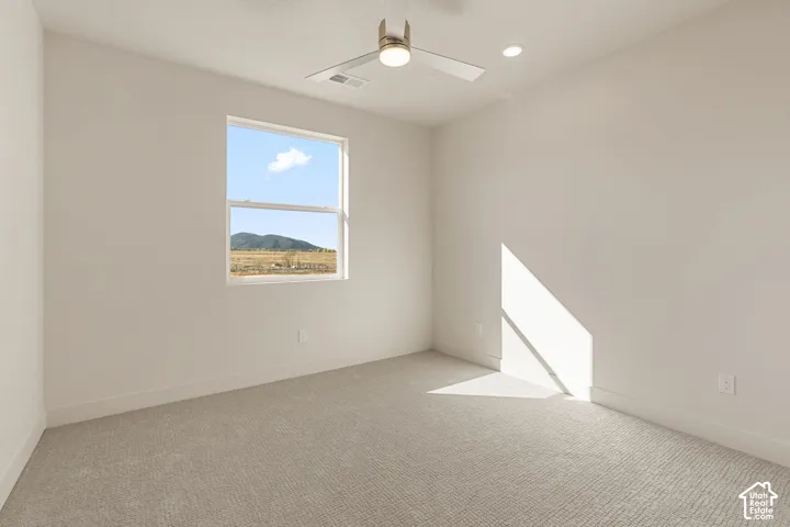 Neutral-toned room featuring plush wall-to-wall carpeting, a multi-blade ceiling fan with integrated lighting, recessed lighting, and a window framing mountain scenery