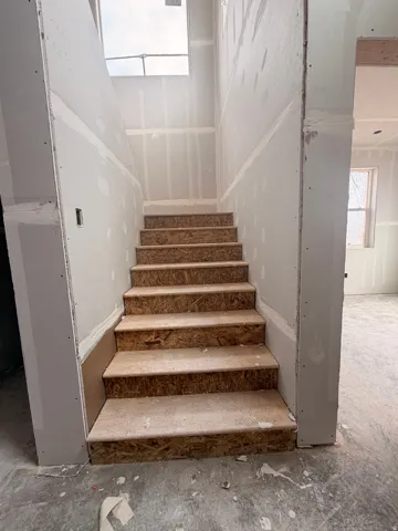 Staircase with OSB treads framed by unfinished drywall