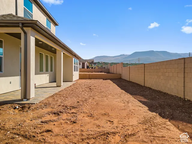 Covered patio with stone-finish pavers, masonry block privacy wall, and mountain backdrop
