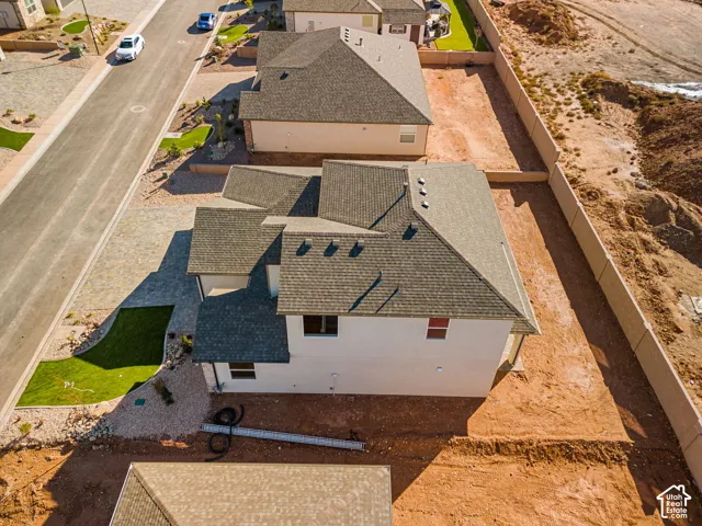 Two-story stucco exterior with a multi-gabled shingle roof, paver stone driveway, and landscaped front lawn area