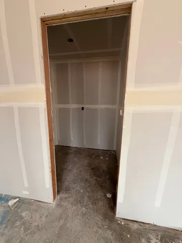 Unfinished interior space with drywall installation, exposed wood framing, and a raw concrete floor, offering a blank canvas for customization