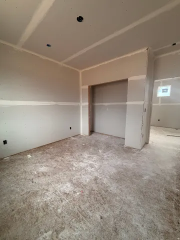 Unfinished interior space featuring drywall installation with taped seams and a prepared ceiling for lighting