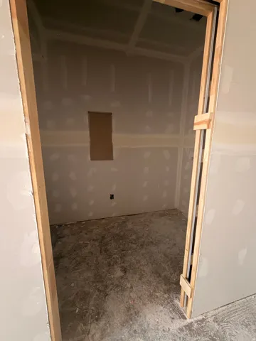 Unfinished interior space with drywall walls, unfinished concrete flooring, and an integrated wall niche