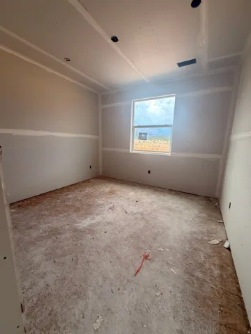 Spacious interior room featuring a single window and unfinished drywall