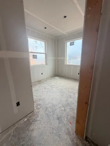 Interior room featuring two window openings, drywall-finished walls, and a ceiling with recessed light openings