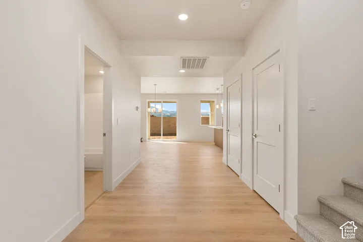 Interior hallway featuring wood-finish flooring, recessed lighting, multi-panel doors, and neutral paint tones