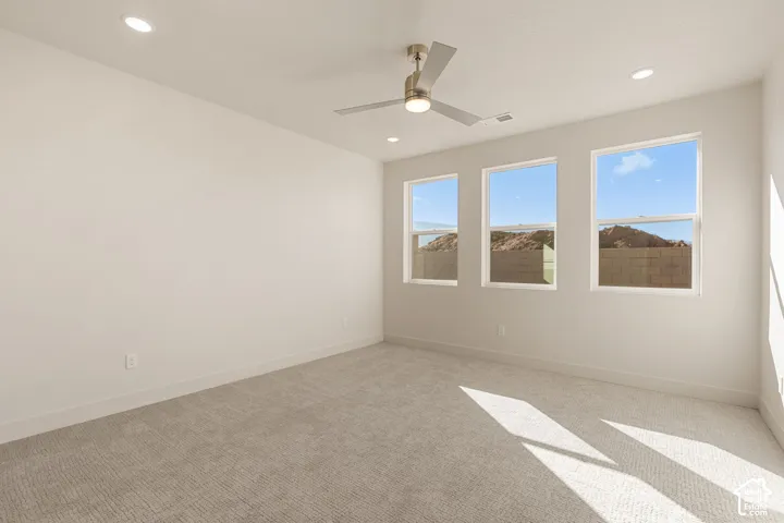 Neutral-toned interior space featuring wall-to-wall carpeting, recessed ceiling lighting, and a brushed nickel ceiling fan with integrated lighting