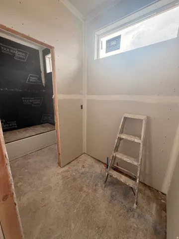 Unfinished interior space featuring drywall installation and a high horizontal window