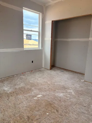 Room featuring a double-hung window, drywall installation, and an open closet space