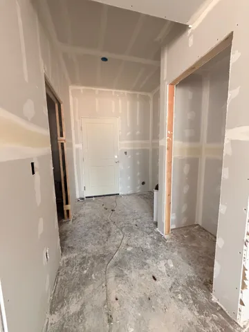 Interior space currently under construction, featuring newly installed drywall and framed doorways