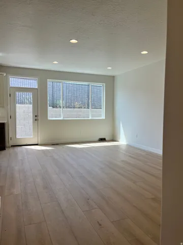 Spacious room featuring wood-finish flooring, recessed lighting, and white walls