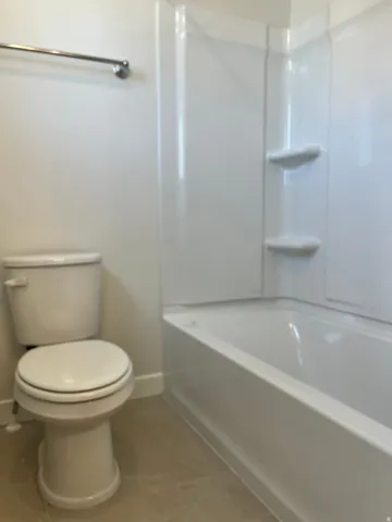 Full white bathtub and shower surround with integrated shelving