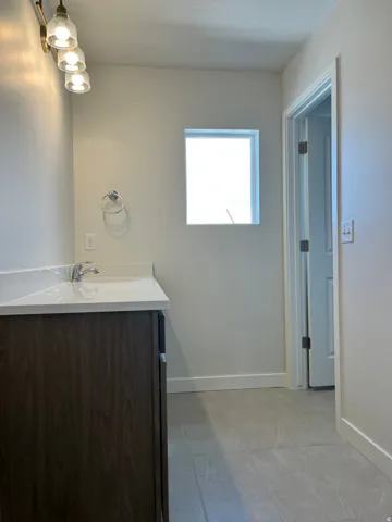 Bathroom vanity featuring wood-finish cabinetry, a white countertop with integrated sink, and a chrome faucet