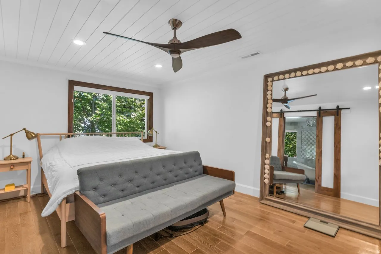 Bright primary suite featuring hardwood flooring and shiplap ceiling with recessed lighting and ceiling fan