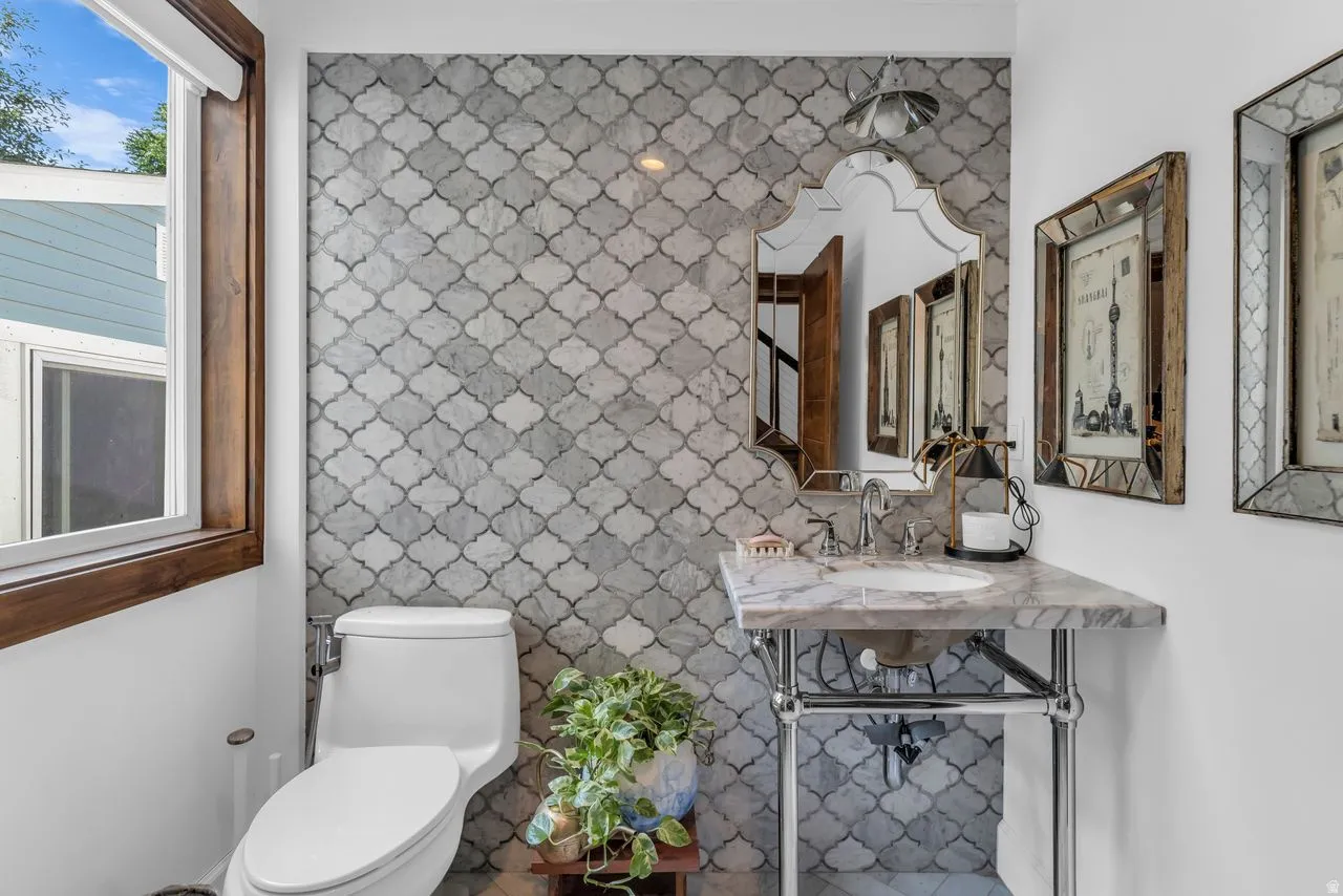 Bathroom featuring a decorative arabesque tile accent wall and a window with wood trim