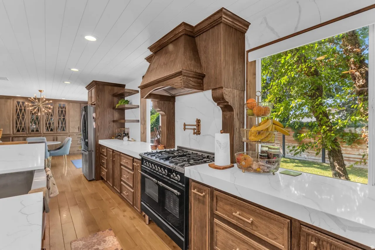 Bright kitchen featuring a built-in gas range, pot filler, and a large window overlooking the backyard