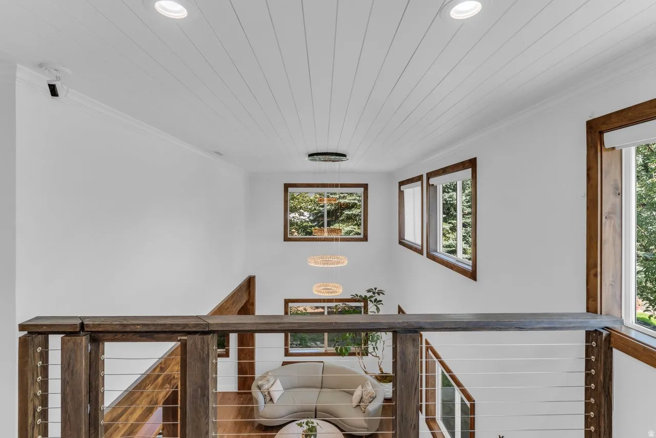 Open loft area with wood railing featuring shiplap ceiling and large chandelier