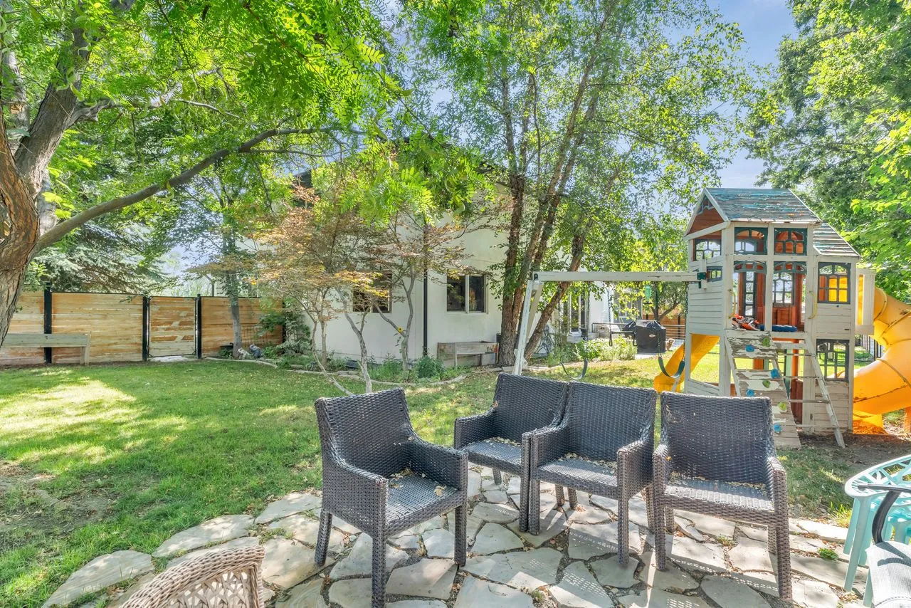 Backyard patio featuring flagstone paving, surrounded by mature trees and a manicured lawn