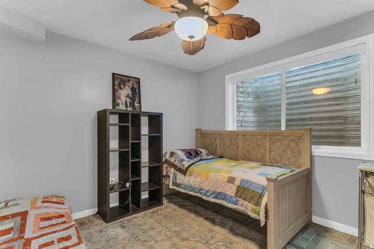 Bedroom featuring a window and a ceiling fan with leaf-shaped blades.