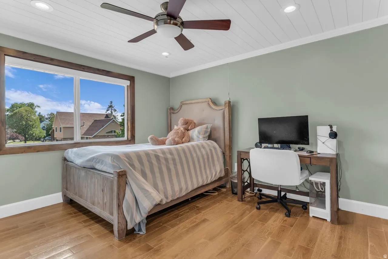 Spacious room featuring hardwood flooring, a white shiplap ceiling with recessed lighting, a ceiling fan, and a large window with wood trim