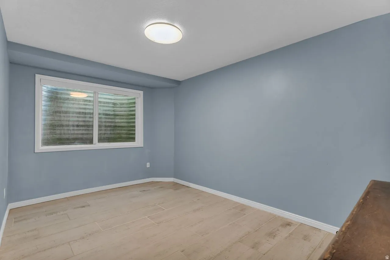 Bedroom featuring light blue walls, light wood-finish flooring, white baseboards, and a window