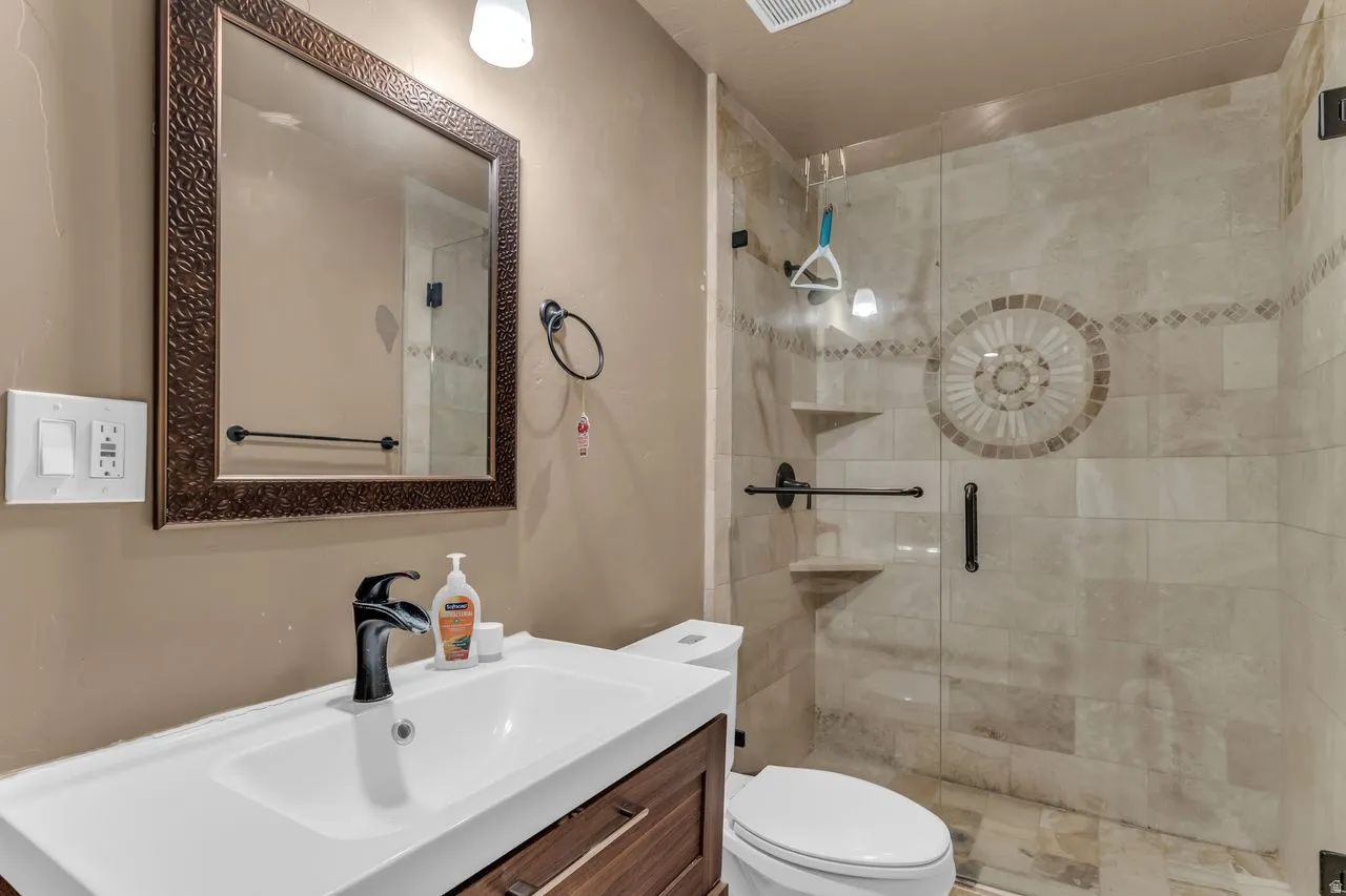 Bathroom featuring a walk-in shower with a glass enclosure, tiled walls, and a decorative mosaic inlay