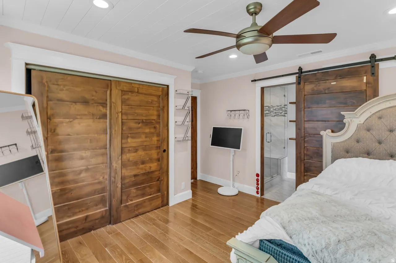 Hardwood flooring throughout featuring a ceiling fan, recessed lighting, and a barn door entry to the shower
