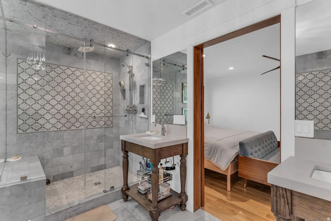 Spacious ensuite bathroom featuring a glass-enclosed shower with patterned tile accent, dual shower heads, and an integrated bench