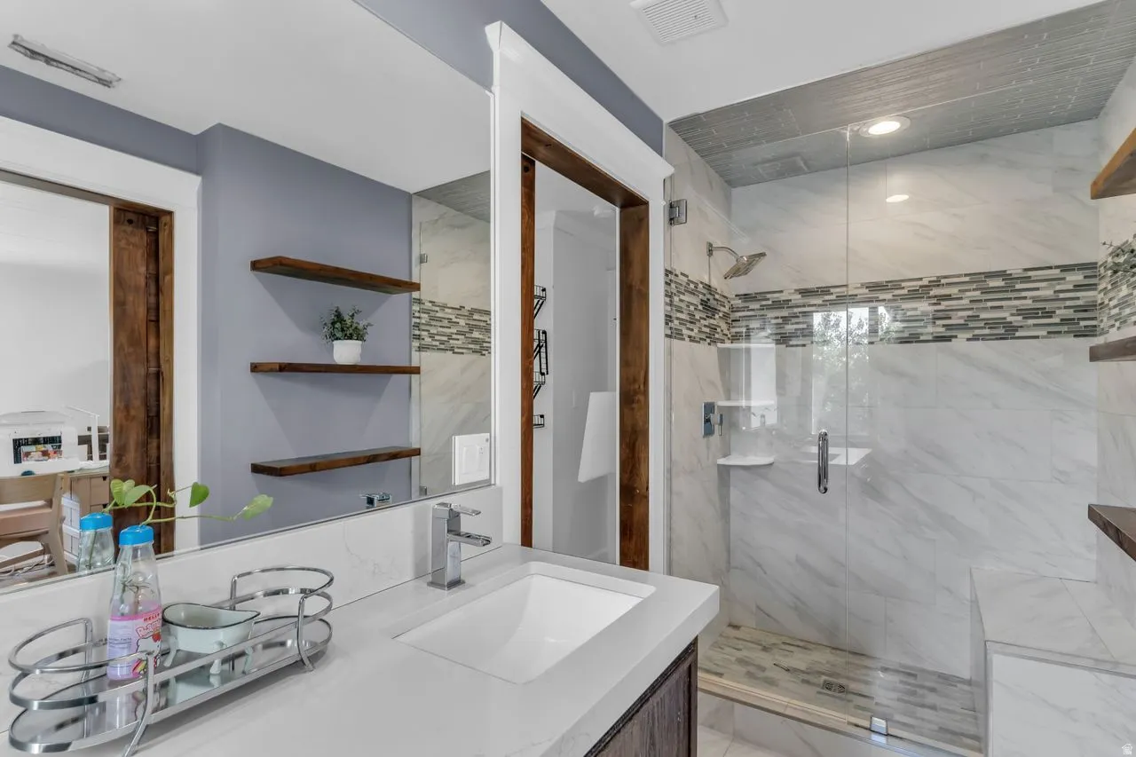 Bathroom featuring a spacious walk-in shower with a glass enclosure, a built-in shower bench, and a tiled accent band