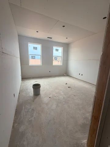 Spacious room featuring two windows, recessed ceiling lighting, and a concrete subfloor
