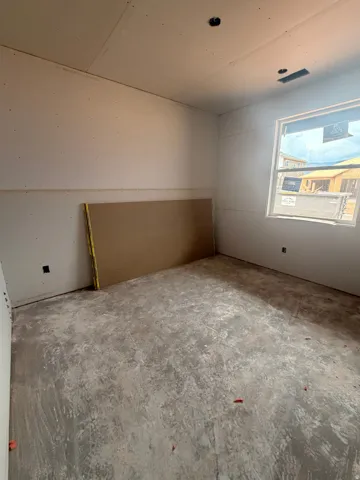Room under construction with unfinished drywall, a single window, and a concrete subfloor