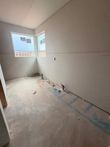 Corner windows provide abundant natural light to this space, featuring unfinished drywall and a concrete subfloor