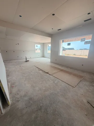 Open-concept interior featuring unfinished drywall, multiple window openings, and visible ceiling recessed lighting fixtures
