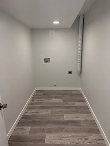 Laundry area featuring wood-finish flooring, recessed ceiling lighting, a dryer vent, and appliance hookups