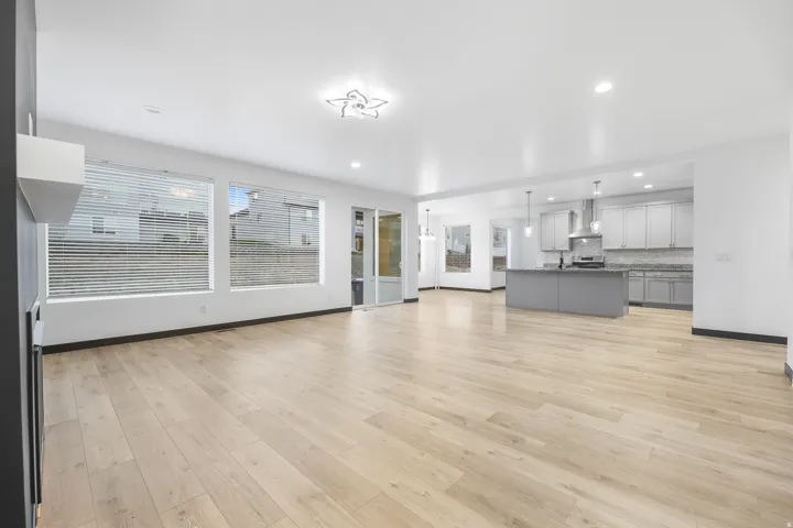 Open-concept living space featuring wood-finish flooring, recessed lighting, and expansive windows with blinds