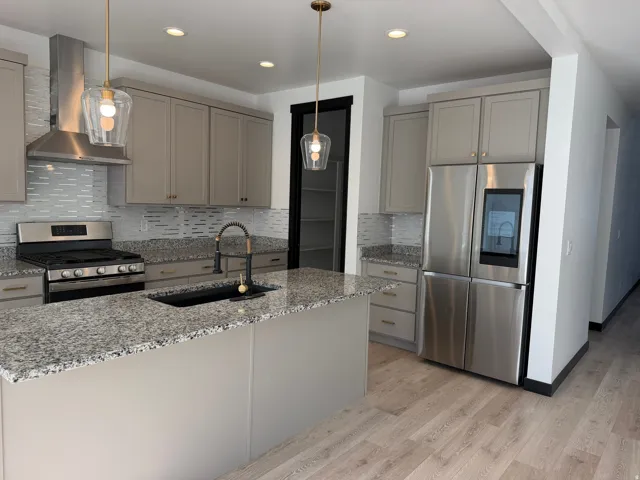Kitchen featuring a central island, granite countertops, stainless steel appliances, pendant lighting, and wood-finish flooring